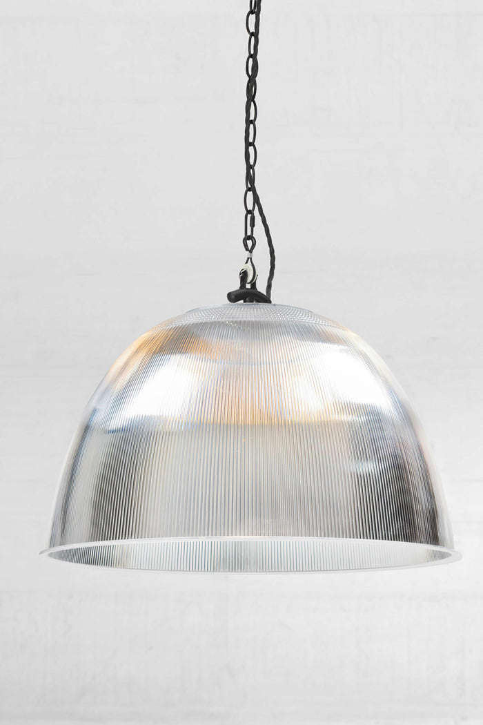 A dome-shaped industrial pendant light with a ribbed Large clear prismatic pendant with black chain style pendant suspension