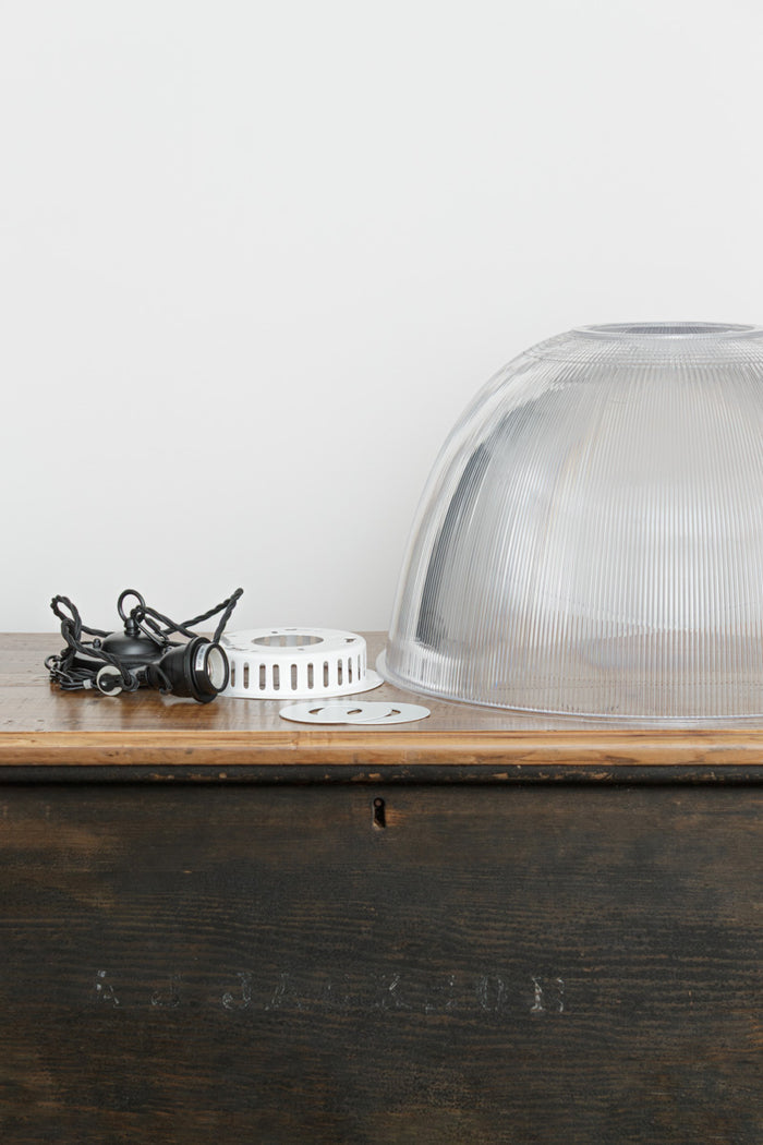 Large clear prismatic shade with black suspension hardware on a timber bench