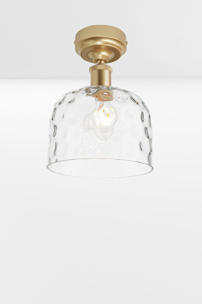 Clear glass shade with dimpled detailing paired with a gold/ brass batten holder.