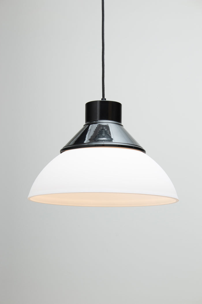 A modern pendant light with a white dome-shaped shade, a black top collar/ shade cover, and a black hanging cord. Homestead Foundry Pendant Light
