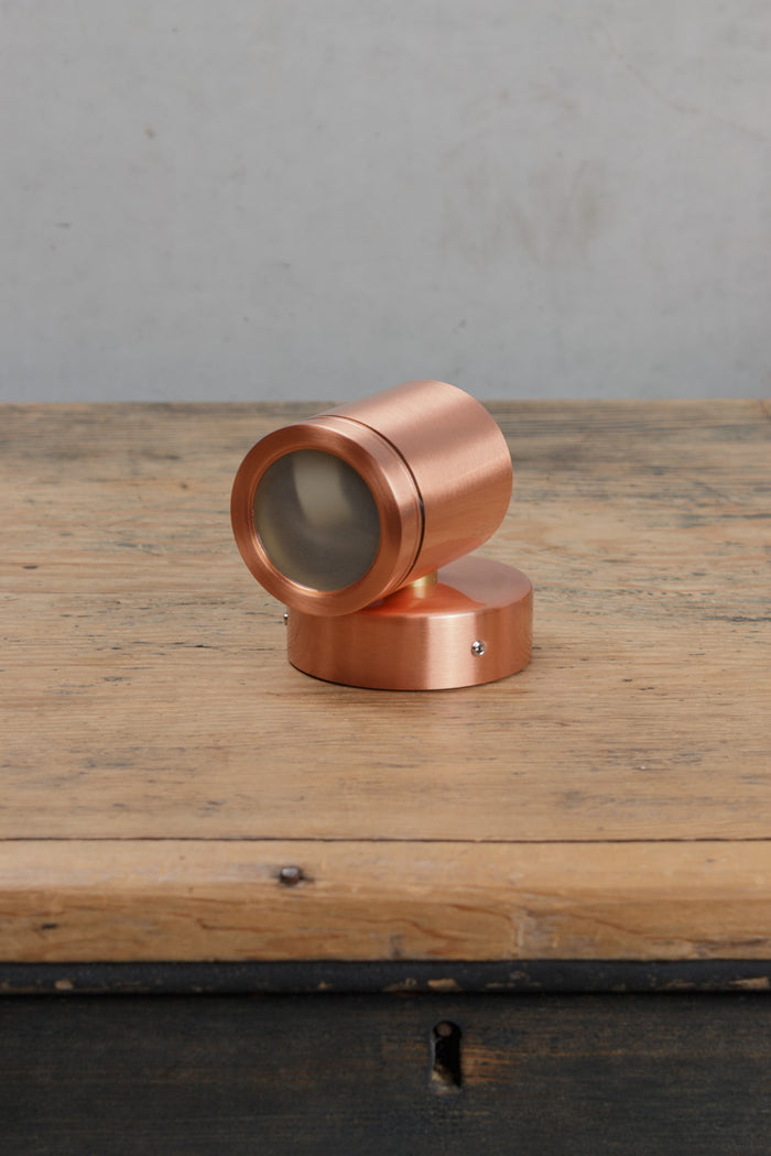 Uninstalled single light, solid copper wall spotlight with polished finish.