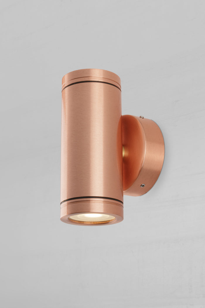 Side view of the solid copper up/down wall spot light with a polished finish.