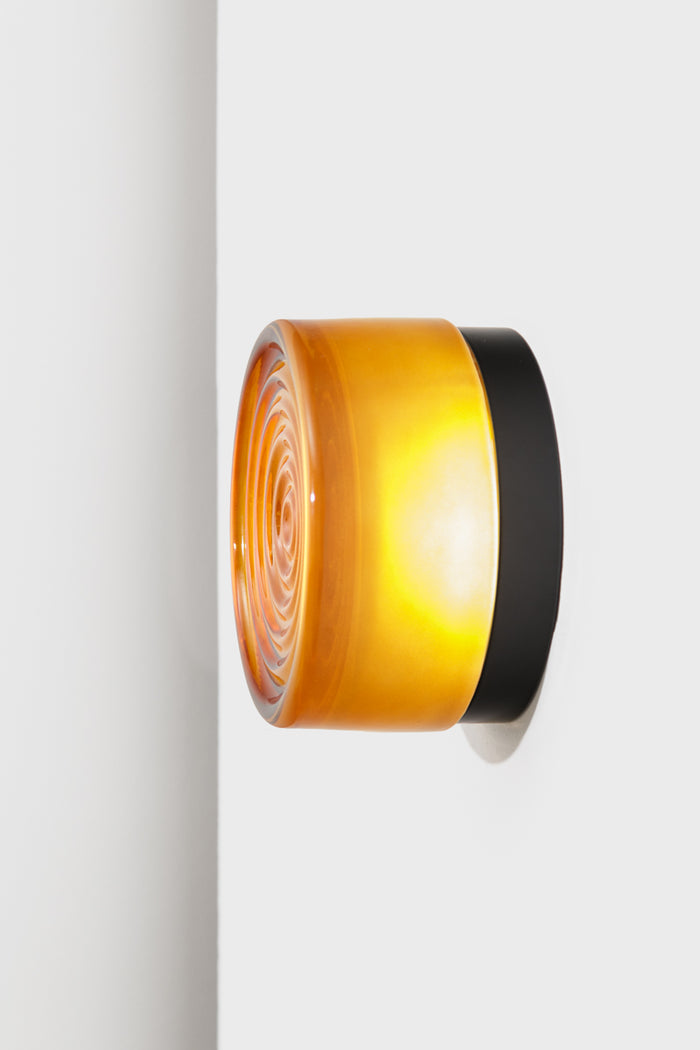 Side profile of the amber LED glass wall light showing the layered glass shade and black mounting base.