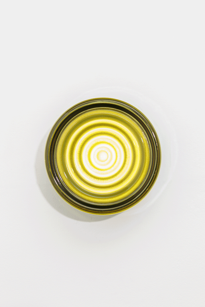 GIF of the green LED glass wall light switched on in a light and dark space, showing circular ribbed glass texture.