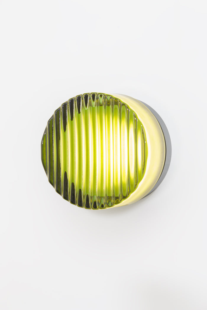 Green ribbed LED wall light shown with light illuminated.