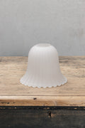 Featuring subtle ridges and scalloped edging, its bell shaped glass shade is enhanced with a frost finish and has a textured appearance.