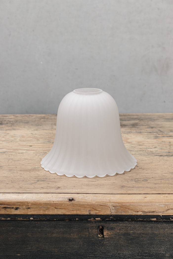Featuring subtle ridges and scalloped edging, its bell shaped glass shade is enhanced with a frost finish and has a textured appearance.