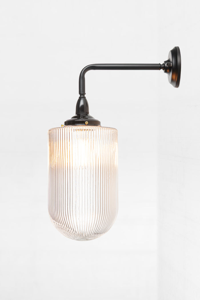 Side view of the large elongated reeded clear glass shade on a black 90 degree outdoor wall light.