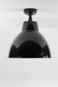 Black outdoor flush mount light with a large steel shade finished in black.