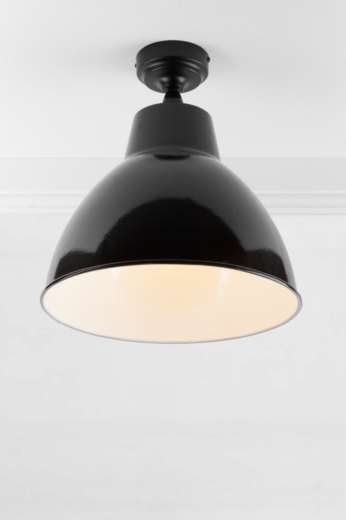 Black outdoor flush mount light with a large steel shade finished in black, showing the white inner.