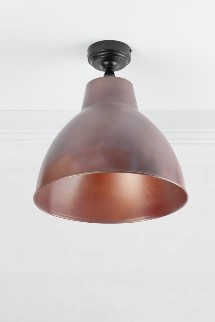 Black outdoor flush mount light with a large solid copper shade with an aged finish.