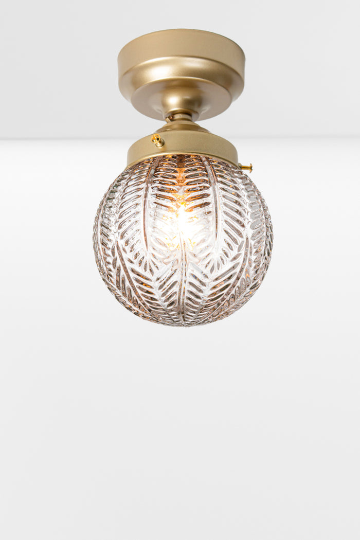 Clear glass orb shade with vintage inspired detailing on a gold/brass batten holder.