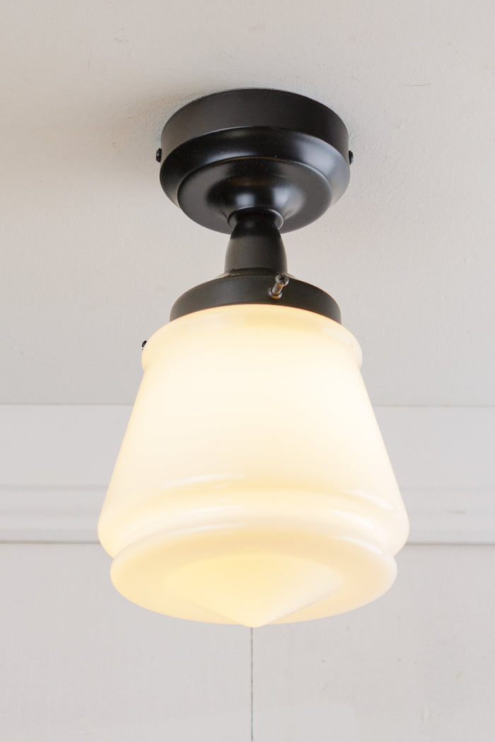 Black batten holder paired with a n opal glass shade on a white ceiling.