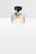Cylindrical clear glass shade with a flat top and chevron detailing, paired with a black batten holder and gallery.