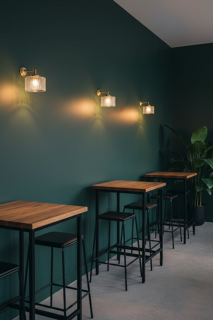 Three Malibu Glass Swivel Wall Lights in solid gold/brass with a clear textured glass shades, over bar high table and chairs in a forrest green coloured eating space.