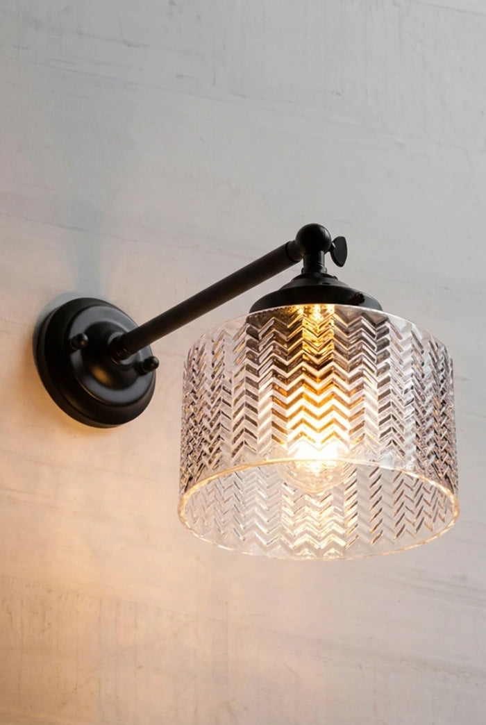 Malibu Glass Swivel Wall Light textured clear glass shade with illuminated herringbone pattern and the long straight arm in black.