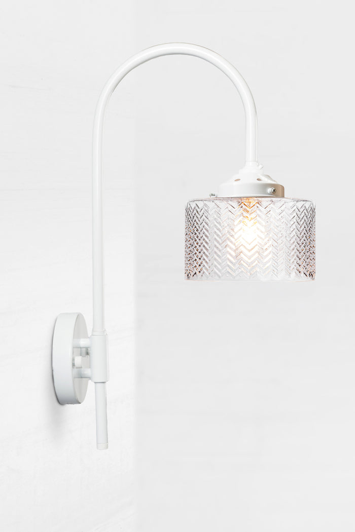 White shepherds hook wall sconce paired with a clear glass shade with a wavy chevron detail.