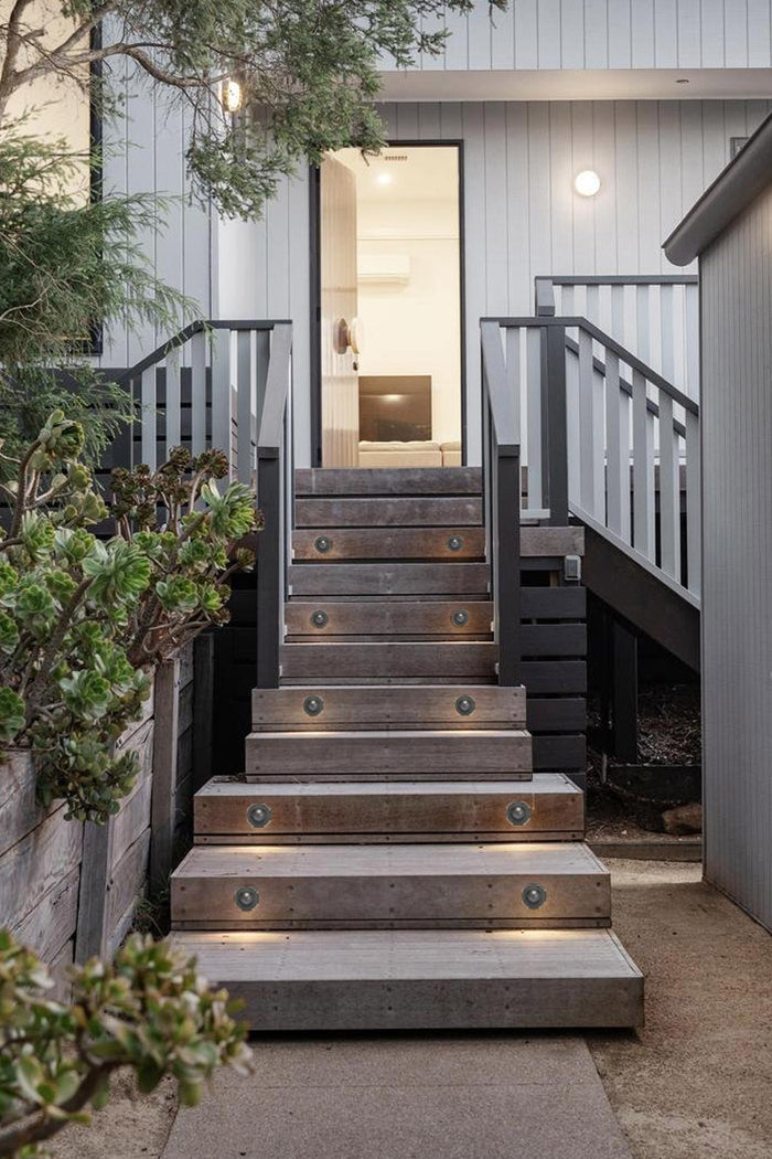 10 charcoal coloured step lights on an outdoor staircase up to a front door.