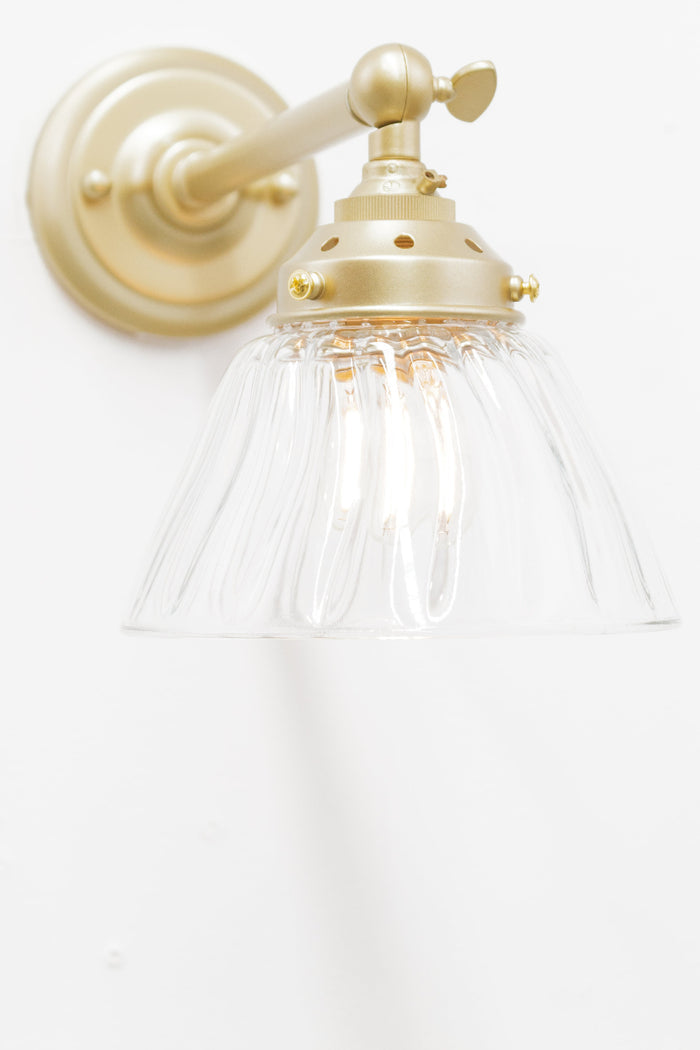 Front view of the long straight wall sconce in golf with a clear shade.