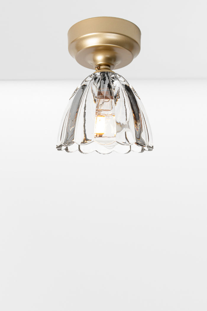 Clear glass shade with scalloped edging on a gold/brass batten holder.