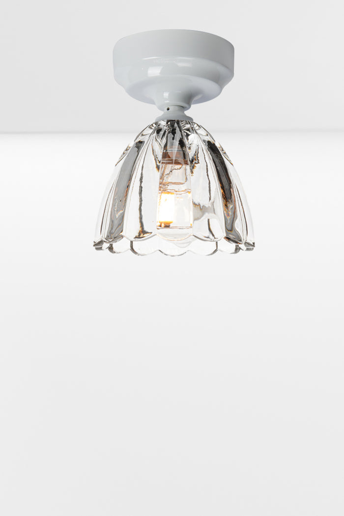 Clear glass shade with scalloped edging on a white batten holder.