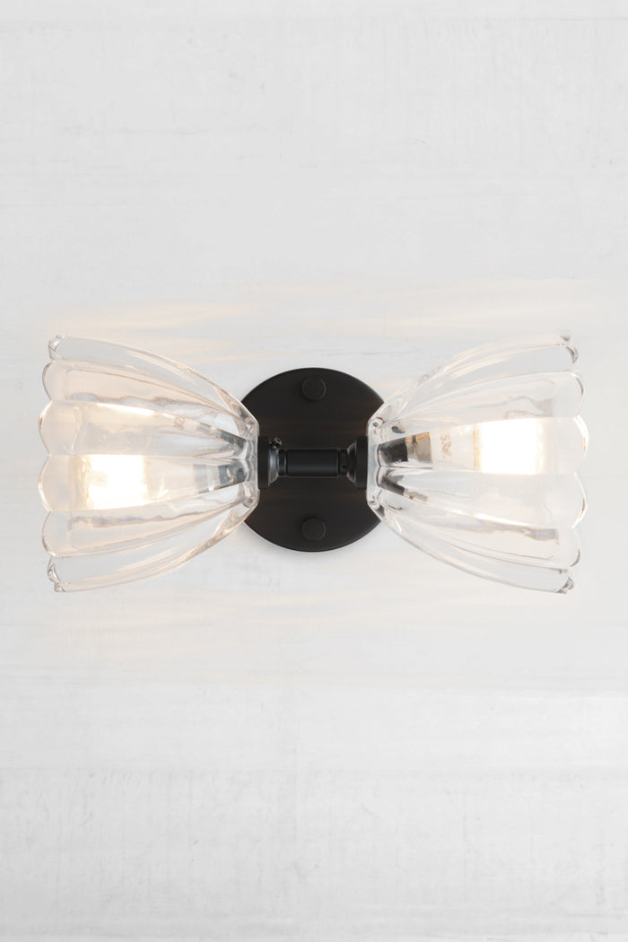 Showcasing a sideways installation of the black double wall light with two clear glass shades.
