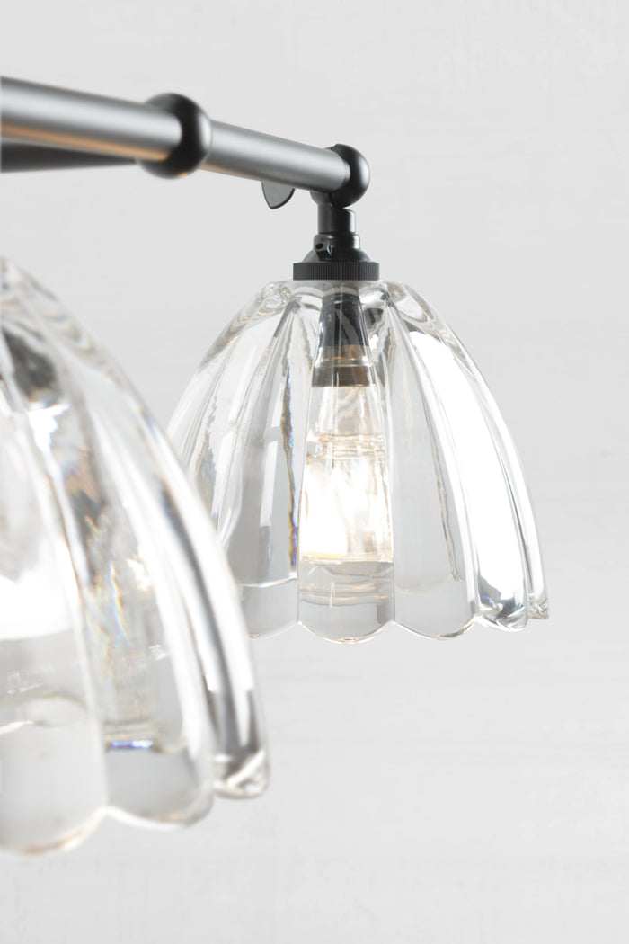 Close up of the shades of the black double swivel wall arm sconce with two clear glass shades.