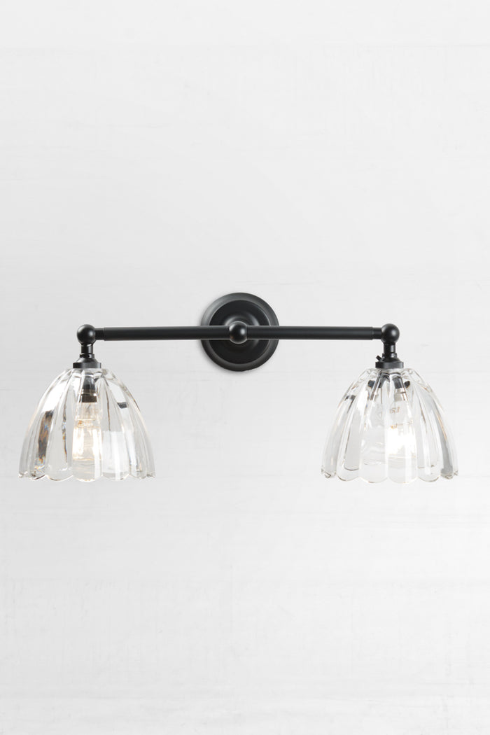 Front view of the black double swivel wall sconce fixture with the two clear scalloped edge glass shades.