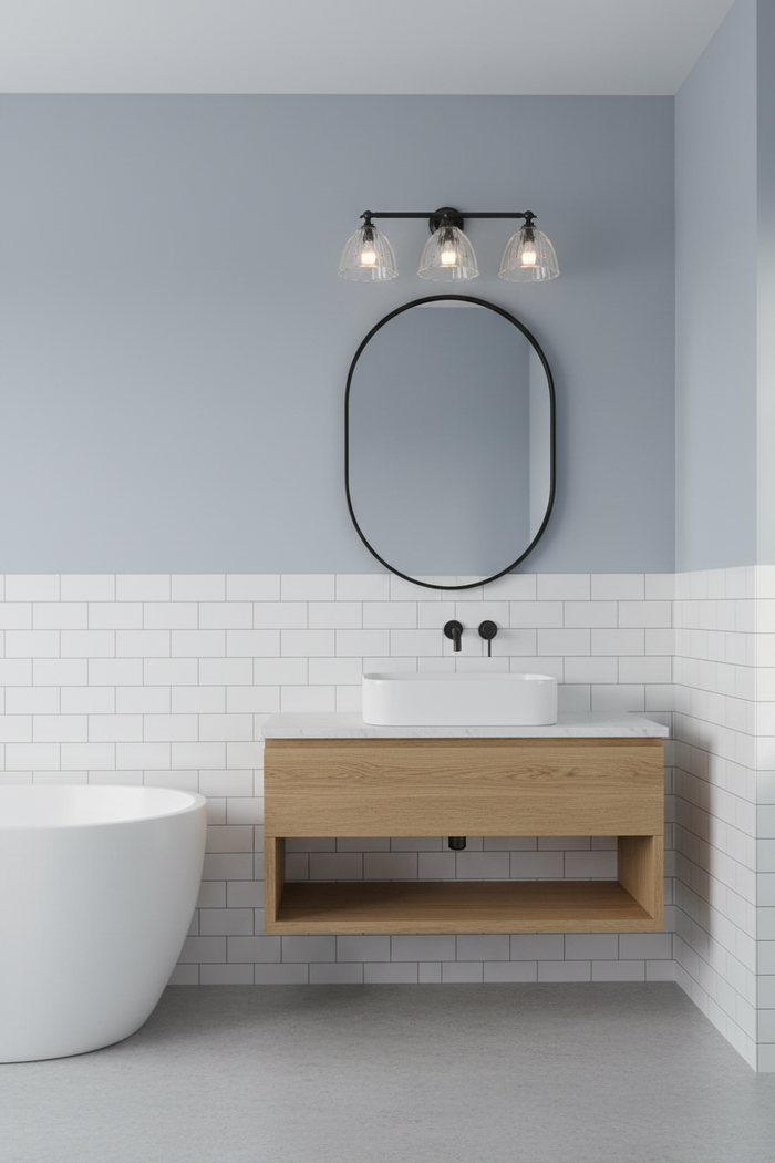 3 light wall light in modern bathroom with wooden vanity, oval mirror, and white bathtub.
