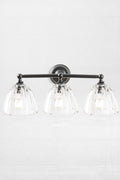 Black triple lamp wall sconce with clear, scalloped edge shades.
