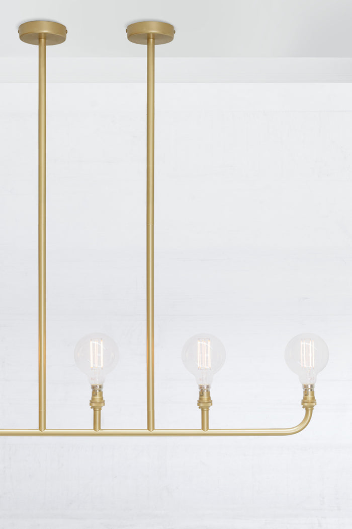 Close up of the five lamp linear chandelier in gold/brass.
