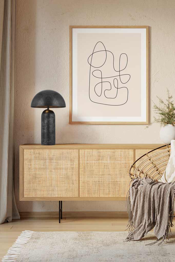 A large Newman Table Lamp in black on a sideboard of a beige toned sitting nook.