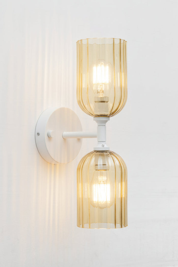 White double wall sconce paired with two eloganted amber glass shades with fluted detailing.