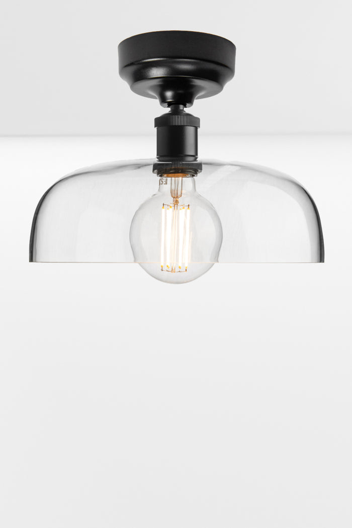 Clear glass dome shade on a black ceiling batten holder.