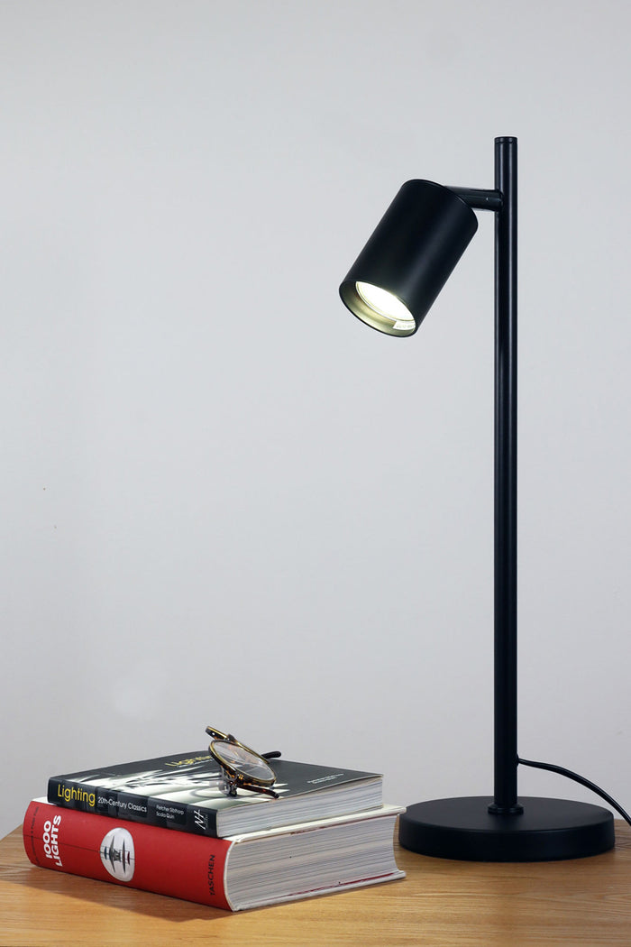 Black desk lamp with chrome accent as a side table lamp with books and glass.