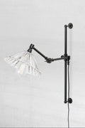 Black swing wall arm with wall plug and a clear glass pleated shade.