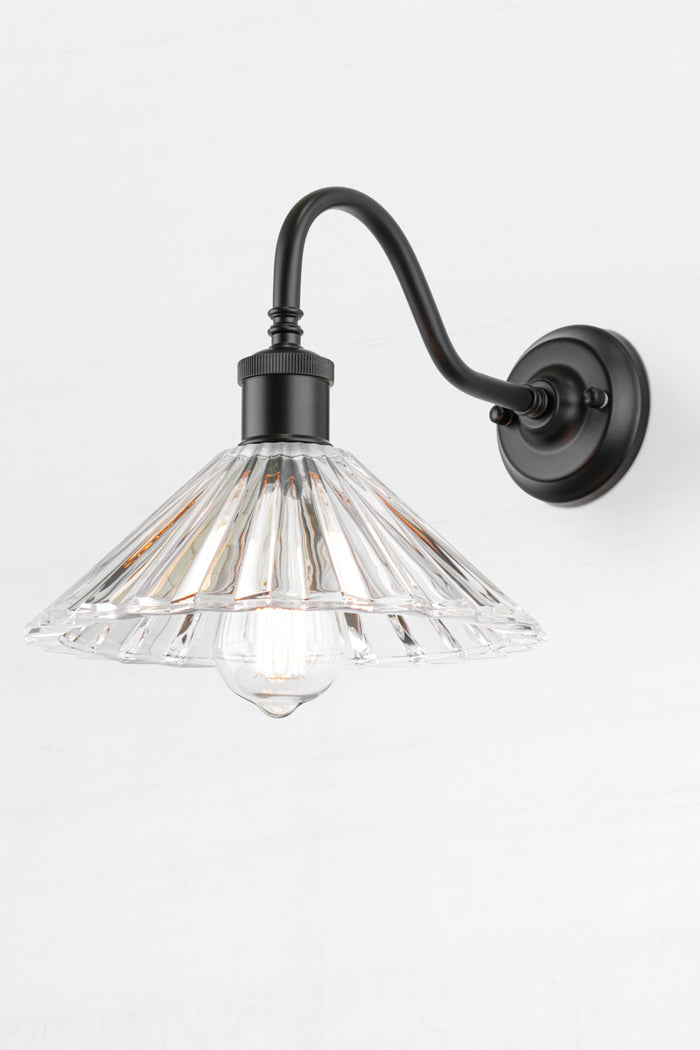 Pleated glass shade with a black gooseneck wall sconce and a clear teardrop bulb.