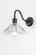 Pleated glass shade with a black gooseneck wall sconce and a clear teardrop bulb.