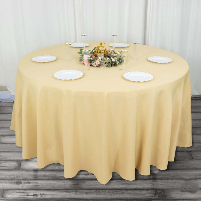 Round table set with a beige tablecloth and decorative centerpiece.