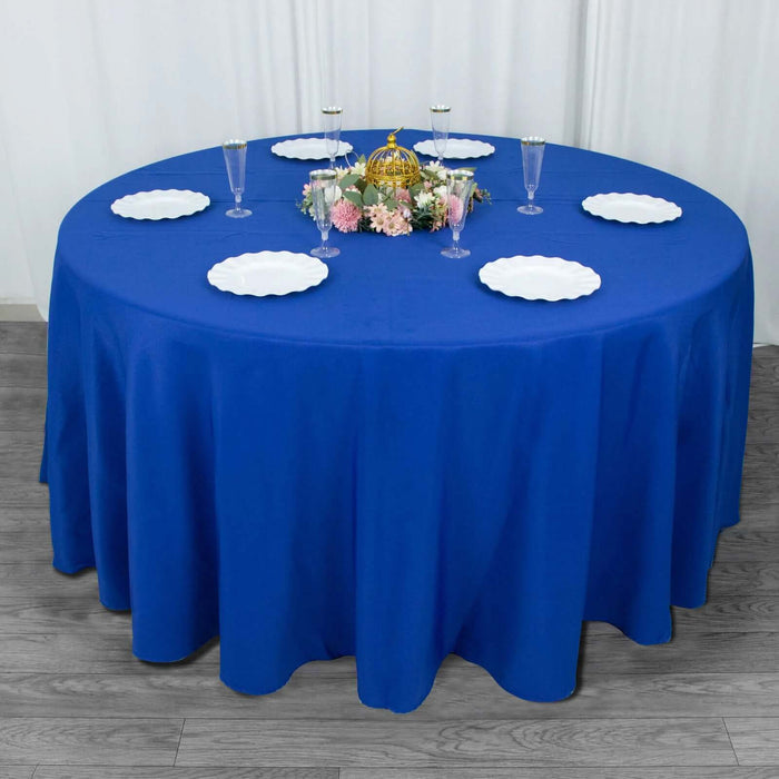 Round blue tablecloth draped over a circular table with plates and decorative centerpiece.