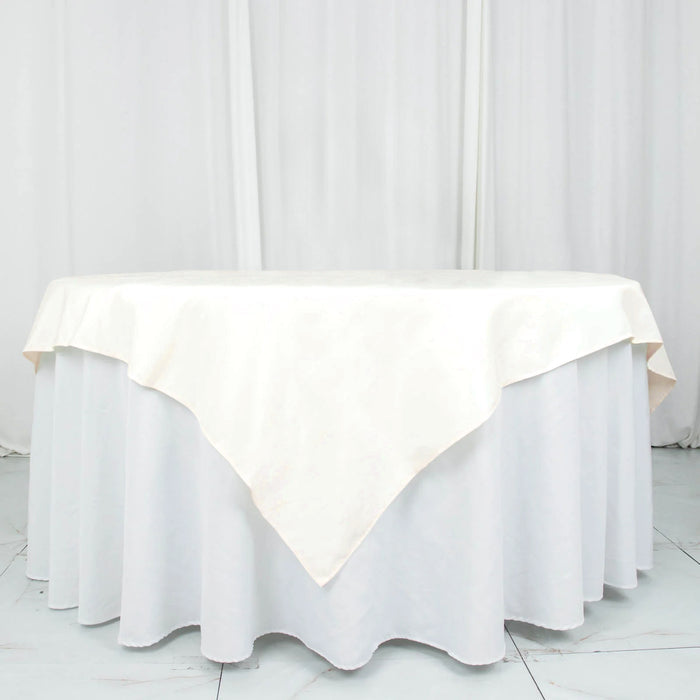 Round ivory tablecloth on a white table with draped edges.