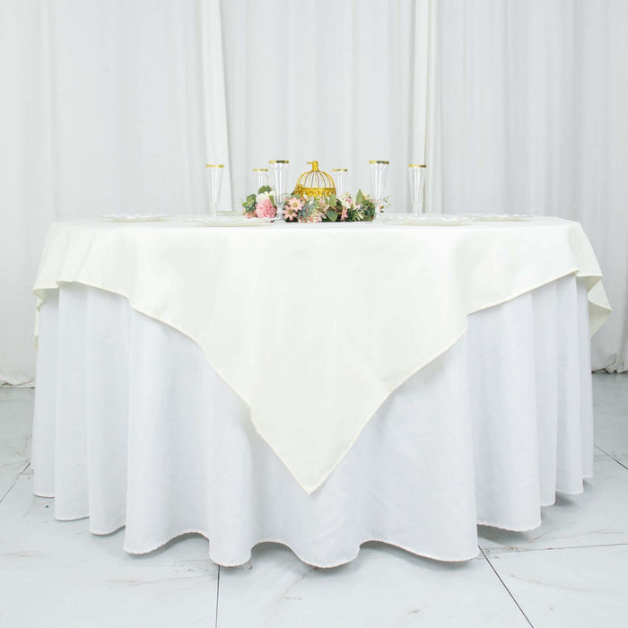 Elegant round table covered with a cream-colored tablecloth and floral centerpiece.