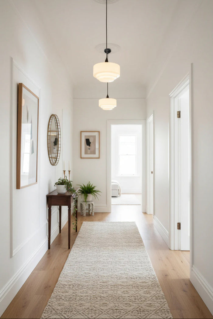 Two opal stepped schoolhouse pendant lights in a light filled hallway.