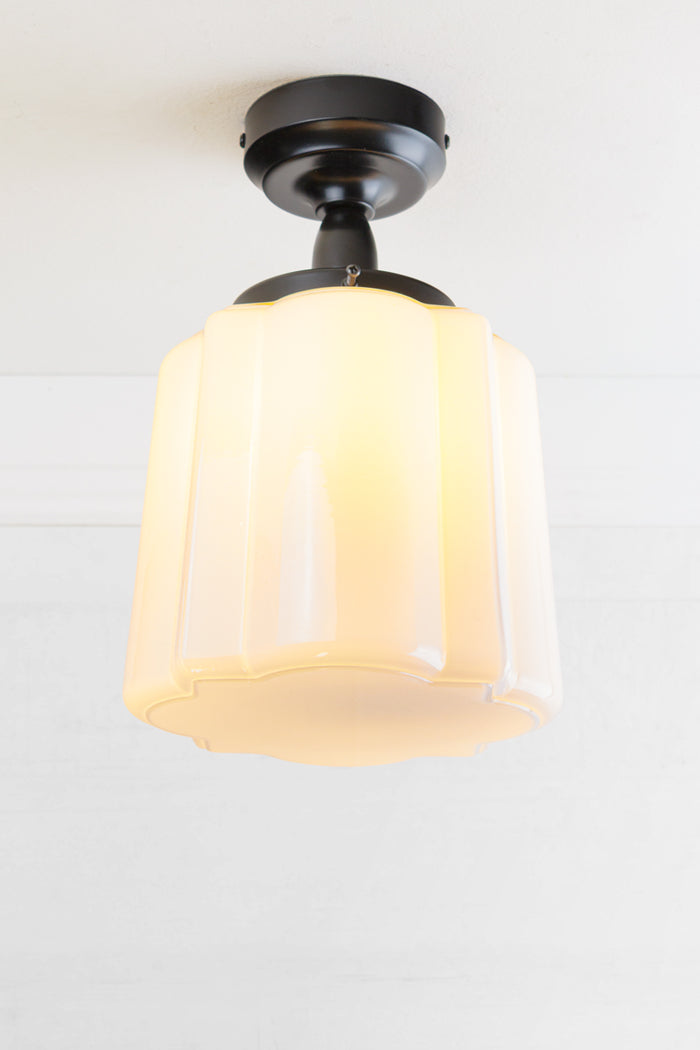 Opal curved glass shade with distinctive deco scalloped detailing, paired with a black batten holder and gallery