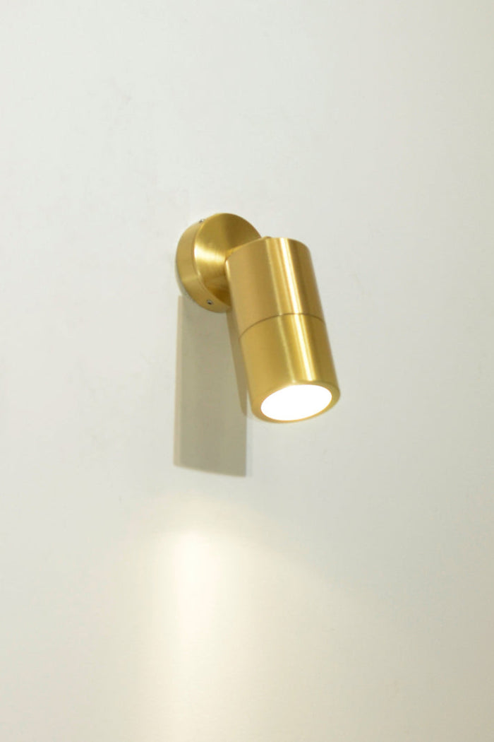 Polished Brass wall light that is iluuminated.
