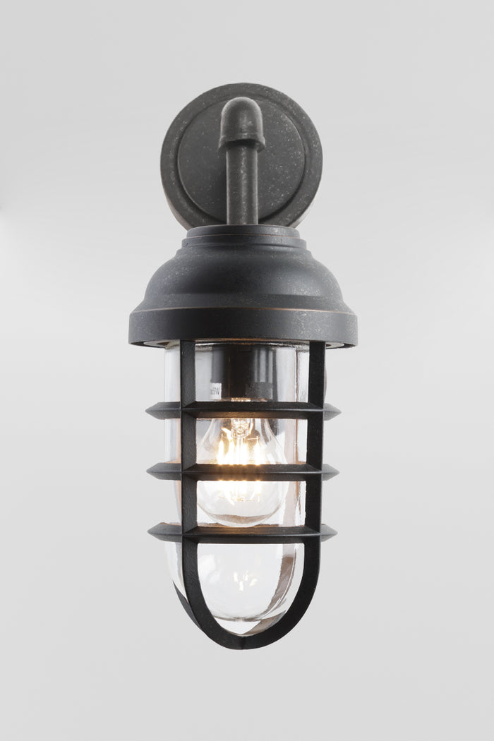 Front view of the Antique Bronze finished steel outdoor wall light with cage detail and a lass shade.