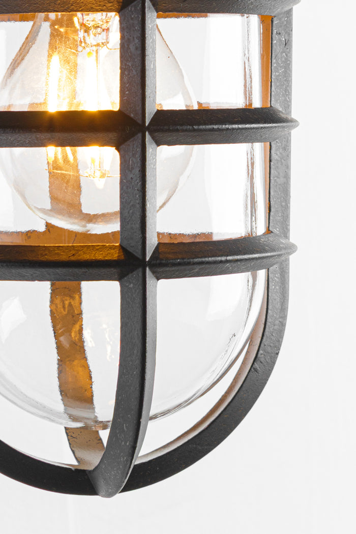 Close up of the clear glass shade, antique bronze cage and clear bulb.