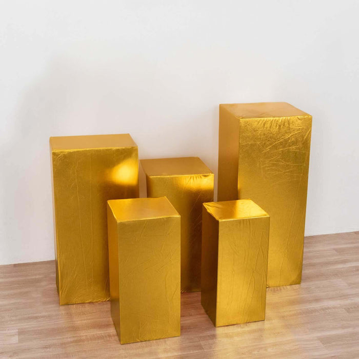 Gold display pedestals in various heights on a light wooden floor.