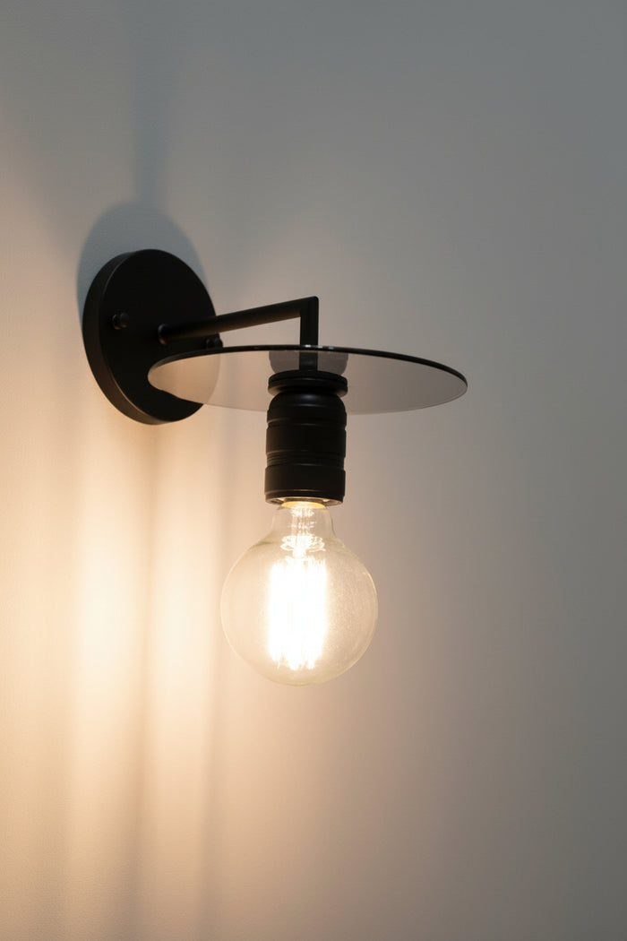 Black disc wall sconce with clear bulb