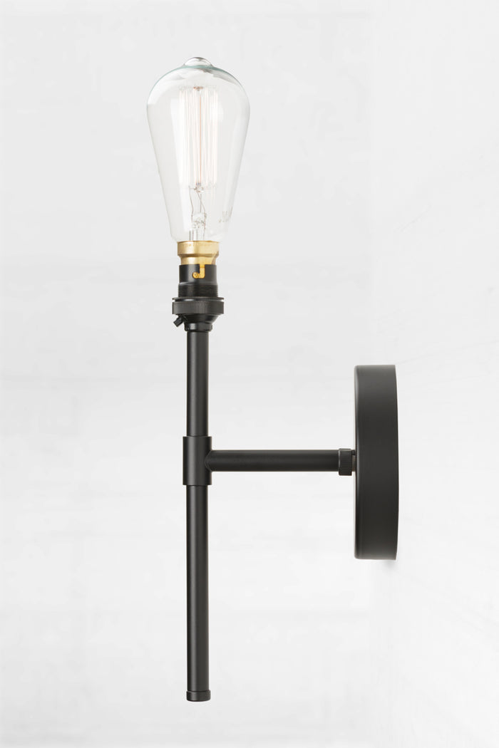 Black stem wall-mounted light fixture with a LED edison style light bulb on a white wall